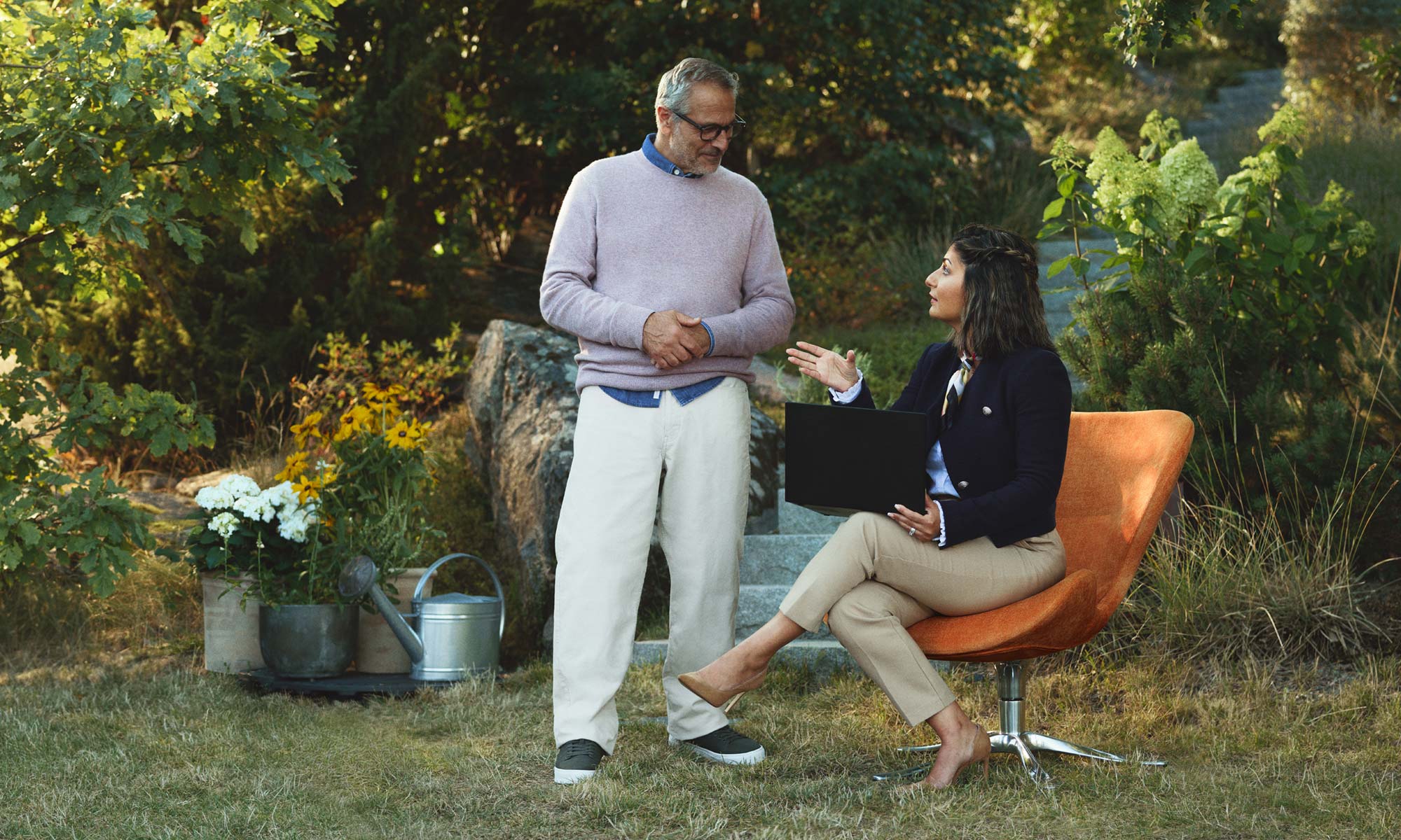 Person sitting in orange chair with person standing next to them