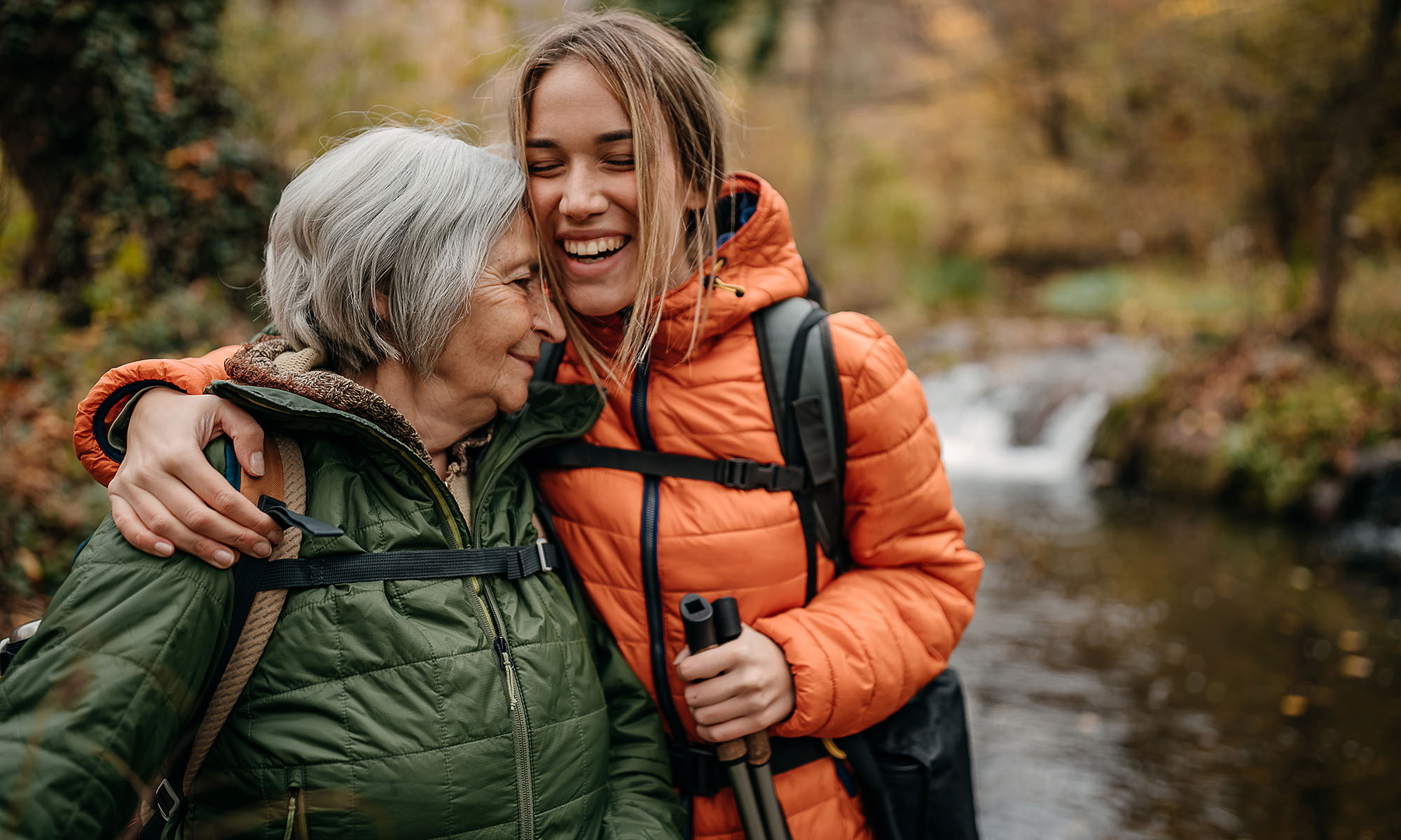 Senior women and her granddaughter hiking on mountain, walking through forest